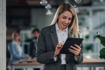 Smiling businesswoman using digital tablet in modern office