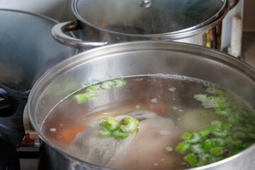 
pork shank and vegetables such as carrots and celery simmering in a large metal pot.