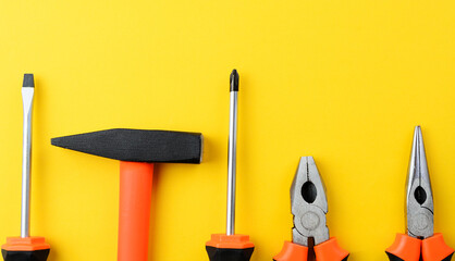 Tool tips on yellow background, screwdrivers, hammer, pliers with empty copy space