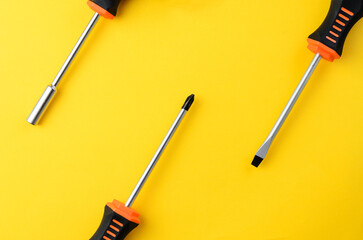 Three screwdrivers partially visible on yellow background with empty space, minimal tool layout
