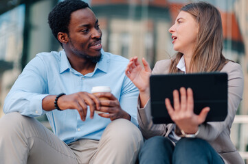 Business colleagues discussing work using tablet outdoors