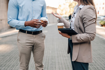 Businesspeople talking and holding coffee during a work break outdoors