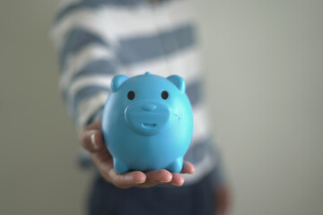 Young asian man is holding the piggy bank and putting cash coins for financial saving for the...