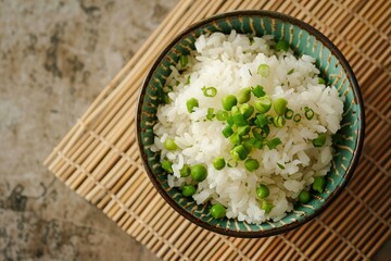 Delicious bowl of perfectly cooked white rice topped with fresh green peas and chopped scallions, served on a bamboo placemat