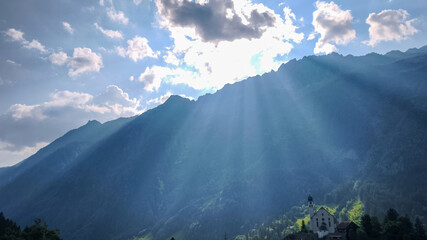 Sunshine rays streaming down on chapel in Swiss alps