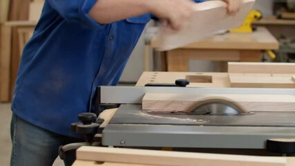 A skilled carpenter is hard at work, cutting wood with a saw in a busy workshop