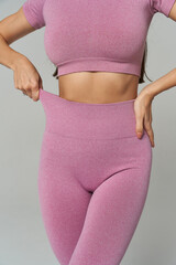Cropped view of a person wearing a matching pink fitness outfit with a short-sleeved top and...
