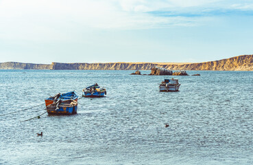A tranquil scene with a fishing boats floating in the calm waters of Pacific Ocean at Paracas National Reserve, Peru.