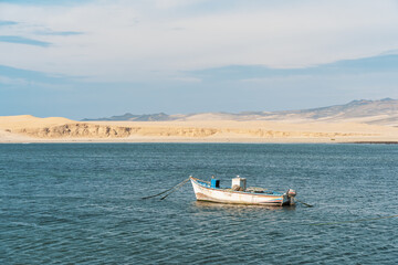 A tranquil scene with a fishing boat floating in the calm waters of Pacific Ocean at Paracas National Reserve, Peru.