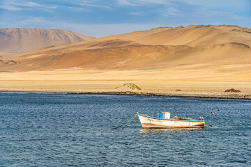 A tranquil scene with a fishing boat floating in the calm waters of Pacific Ocean at Paracas National Reserve, Peru.