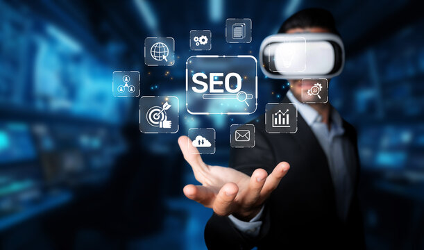 A businessman wearing virtual reality glasses interacts with digital icons representing SEO and marketing strategies, showcasing innovation in a tech-driven environment. XDMCP - Powered by Adobe