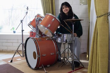 latina teenage girl smiles while practicing drums