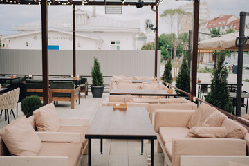 Modern and stylish outdoor seating area featuring soft armchairs, elegant tables, lush greenery, and a casual yet inviting atmosphere, ideal for dining or relaxing with friends and family.