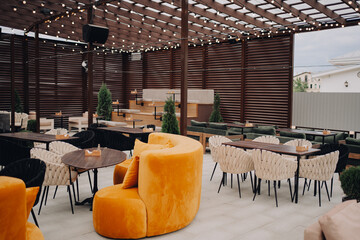 Elegant outdoor seating area featuring modern chairs, a vibrant orange couch, decorative plants,...