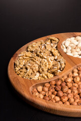 Tree minazhnitsa with walnuts, hazelnuts, pistachio on a black background
