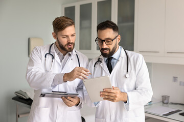 Focused male Hispanic physician man asking coworker for help, advice, professional support, showing...