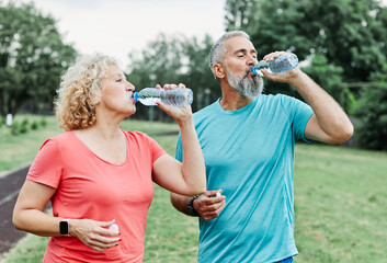 Smiling active mature mid aged couple jogging exercising and having fun and laughing together...