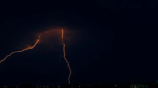 Dramatic Night Lightning Strike over Cityscape - A powerful lightning bolt illuminates the night sky above a dark cityscape.