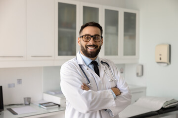Happy confident handsome healthcare professional man posing for clinic profile portrait, keeping...