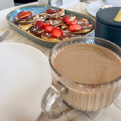 Delicious breakfast spread featuring fluffy pancakes topped with strawberries and syrup, served alongside a warm cup of coffee in a cozy dining setting with inviting ambiance