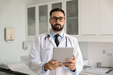 Serious handsome Hispanic doctor man in lab coat posing for healthcare professional profile...