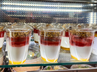 Delicious layered dessert in transparent cups featuring yogurt, fruit compote, and granola,...
