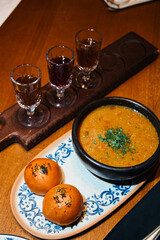 Cheese, vegetable soup, with rolls, on a long plate, next to branded liqueurs, liqueurs, deep plate, served in a restaurant, cafe, bar