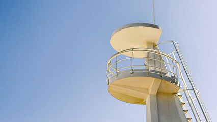 White lifeguard tower on blue sky as a background. Image suitable for beach safety, tourism, or coastal architecture context. Copy space for text.