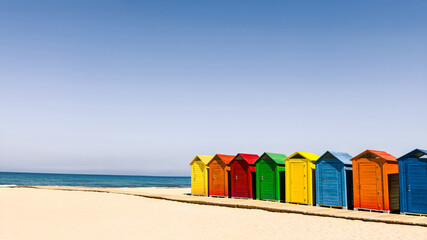 Vibrant cabins line on quiet sandy and sunny beach in Spain. For travel, summer, or vacation...