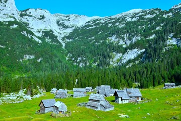Laz alpine pasture with wooden huts at a plain bellow the mountains in Julian alps, Gorenjska, Slovenia