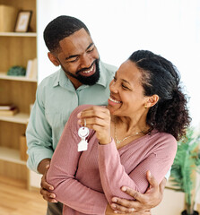 Portrait of a young couple unpacking, holding apartment keys, moving in and relocation to a new...