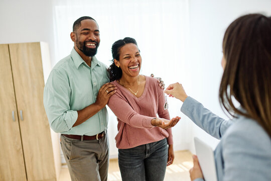 Young black couple receiving keys of new apartment from their real estate agent, standing in the new home
