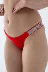 Red women's briefs on the model. young woman's body in red thong panties