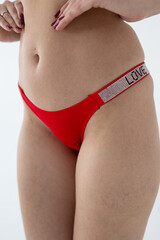 Red women's briefs on the model. young woman's body in red thong panties