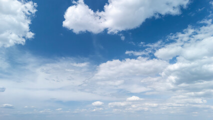 Expansive blue sky with fluffy white clouds creates a serene atmosphere. Ideal for backgrounds,...