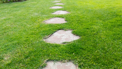 Stepping stones lead through lush green grass, creating a serene pathway in a well-maintained...