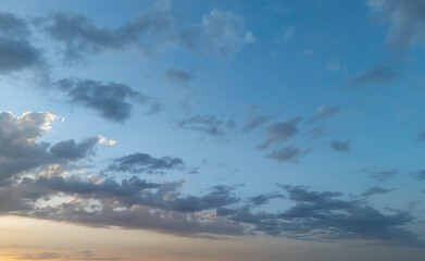 Vibrant sky filled with dynamic clouds at sunset, showcasing a beautiful blend of blue and orange...