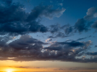 Stunning sunset view over a vast sky filled with rich clouds, showcasing vibrant colors of orange...