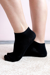Female feet in black socks on carpet