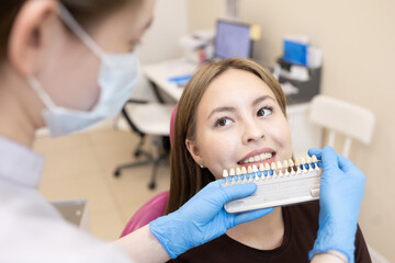 The dentist selects the color of the enamel. The dentist selects a shade of tooth enamel using a special scale of the table