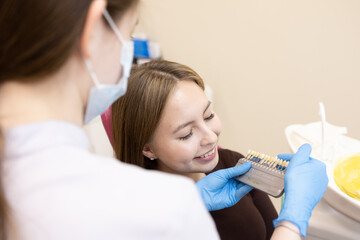 The dentist selects the color of the enamel. The dentist selects a shade of tooth enamel using a...