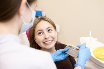 The dentist selects the color of the enamel. The dentist selects a shade of tooth enamel using a...