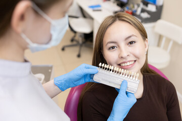 The dentist selects the color of the enamel. The dentist selects a shade of tooth enamel using a...