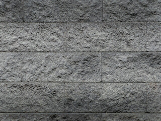 Textured gray stone wall background with a rough surface. The wall features horizontal blocks with...