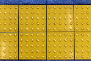 Close up of yellow Tactile paving (also tenji blocks, after name for Japanese braille) a system of...
