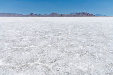 White salt pan of the Bonneville Salt Flats a remnant of the Pleistocene Lake Bonneville near Wendover, UT, USA with in background the mountain range against a blue sky