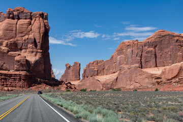 Drivers perspective over the road approaching the Park Avenue rock formation against a blue sky in Arches National Park, Moab, UT, USA