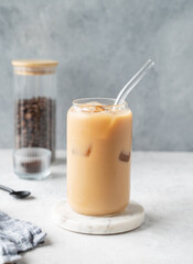 Ice latte coffee in a glass with milk on a marble board on a  light background with coffee beans