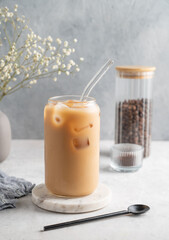 Ice latte coffee in a glass with milk on a marble board on a  light background with coffee beans