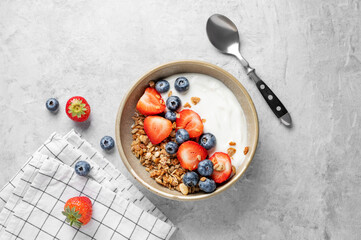 Natural yogurt with granola, blueberry and strawberry in a bowl on a light background